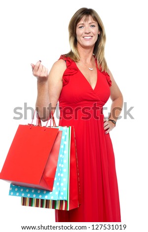 Lovely middle aged lady striking stylish pose with vibrant colored shopping bags.