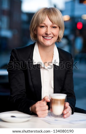 Confident smiling corporate lady holding coffee mug and posing.