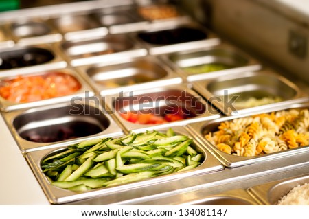 Assortment of food in trays laid out on a restaurant counter-top.