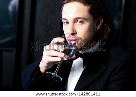 Handsome young guy drinking wine at business party.