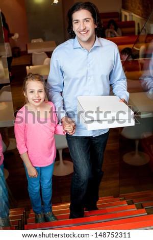 Father holding daughters hand and pizza boxes