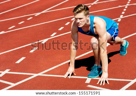 Young muscular athlete is at the start of the race
