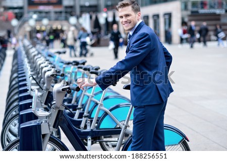 Smiling businessman take his bicycle from parking