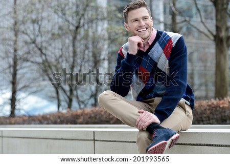 Handsome young guy sitting on the curb
