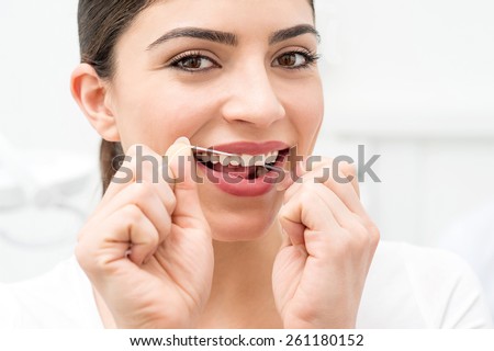Young woman using dental floss in her mouth