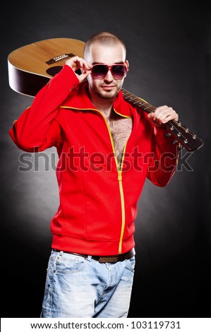 young guitarist stand and holds a guitar in his hands. on a black background