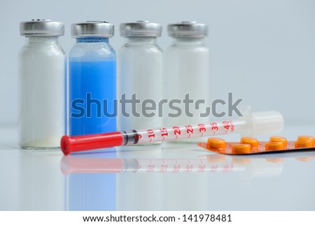 insulin syringe, pills and vials for injection, with white and blue mortar. objects in macro mode