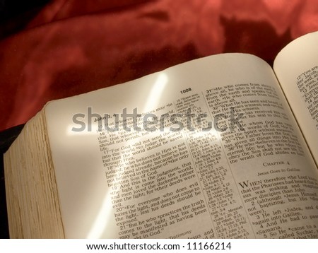 Cross light shape angled across Bible page open to John 3:16