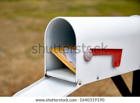 Close up of a mailbox opened with the contents of the mailbox showing with shallow depth of field