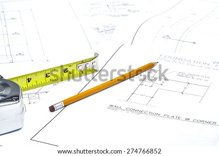 A set of blueprints with tape measure and pencil