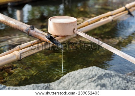 Traditional Japanese bamboo fountain dripping water with ripples in a basin