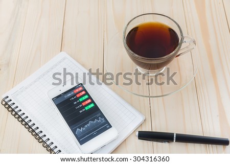 view of stock market application on touchscreen smartphone, Modern workplace with mobile phone