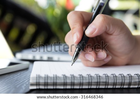 Hand hold a pen writing on the notebook, female hands with pen writing on notebook