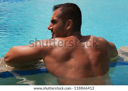 Back side view of tanned Man relax and enjoy at swimming pool. Horizontal shot, outdoors.