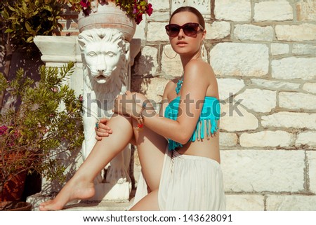fashion shot of young female in summer outfits near a statue. summer soft colors. vertical shot.