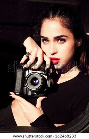 Elegant  female photographer holding a digital camera. Outdoors vertical shot . Attractive woman.