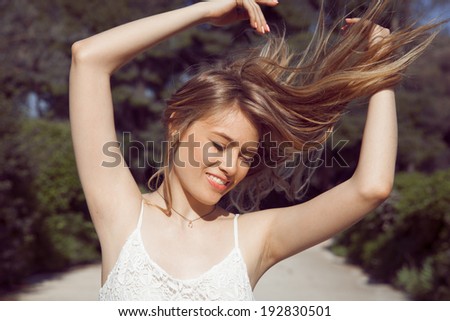 Beautiful model in short dress in field. Long hair blowing in the Wind. Backlit, Warm Color Tones. outdoors shot, horizontal
