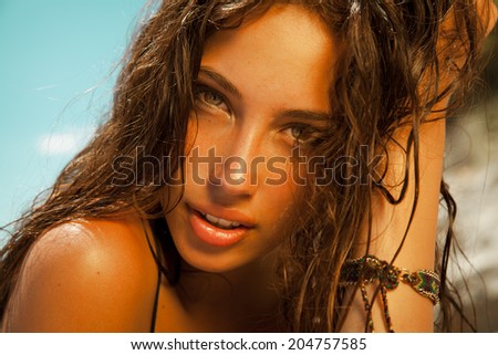 beauty portrait of attractive brunette with golden tan and wet hair. Toned in warm colors. horizontal shot by the sea.