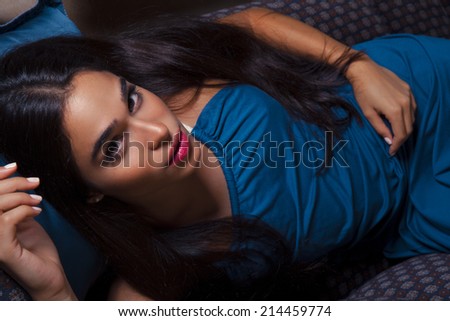 Closeup fashion portrait of young sexy woman relaxed on comfortable luxury sofa. Blue Princess. Indoor, studio shot. toned in warm colors. horizontal shot