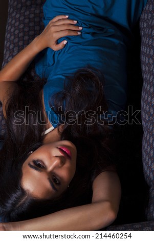 Closeup fashion portrait of young sexy woman relaxed on comfortable luxury sofa. Blue Princess. Indoor, studio shot. Toned in warm colors. Vertical shot