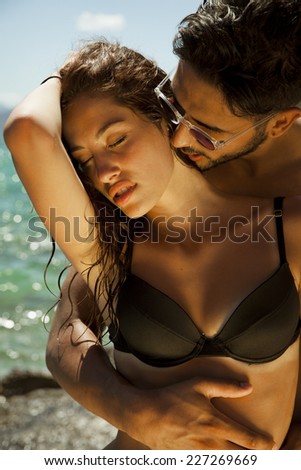 Sexy young passionate couple in bikini. Summer style. Toned in warm colors. Vertical shot
