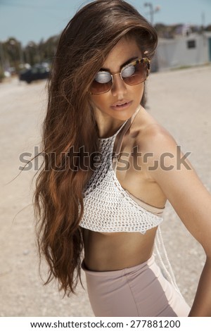 Attractive summer woman with long shine hair on the beach. Vertical shot, outdoors