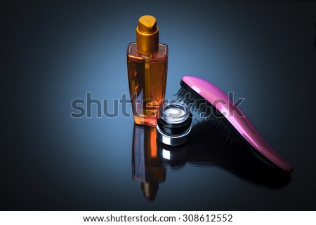 Various bottles of health and beauty products and hair brush on blue background with reflection. Copy space for your text. Studio shot, Horizontal