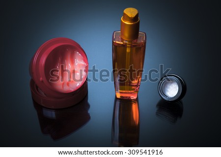 Various bottles of health and beauty products with hair mask on blue background with reflection. Copy space for your text. Studio shot, Horizontal