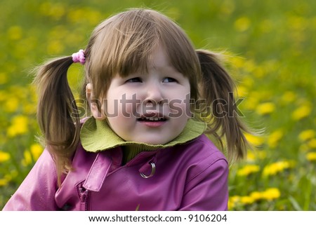 Girl with tails in pink coat in dandelions field