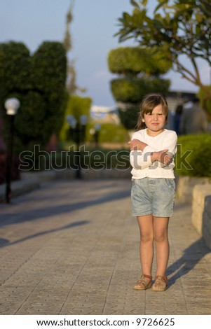 Little girl frozen of strong wind standing in sunset lights