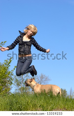Young woman jumping in the sky, dog watching