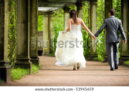 Bride and groom walking away in summer park outdoors
