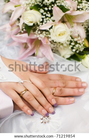 hands of new married with golden rings and bouquet