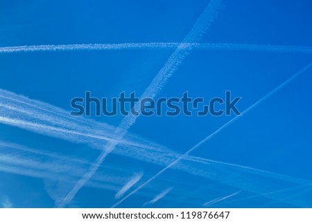 blue sky with vapor trails from planes that intersect and are parallel