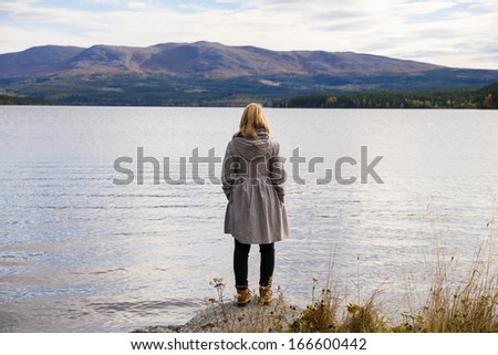 alone thinking woman standing on a stone and looking out over a beautiful mountain landscape