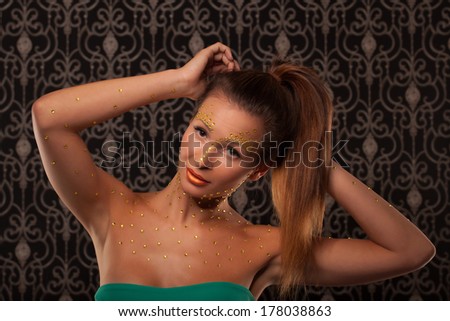 studio portrait of beautiful female woman with futuristic cristal makeup looking up
