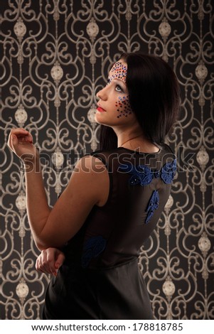 studio portrait of beautiful female woman with futuristic cristal makeup looking up with vintage background