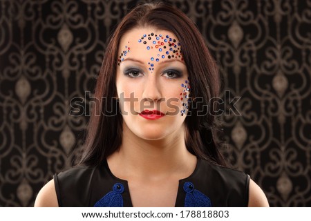 studio portrait of beautiful female woman with futuristic cristal makeup looking up with vintage background