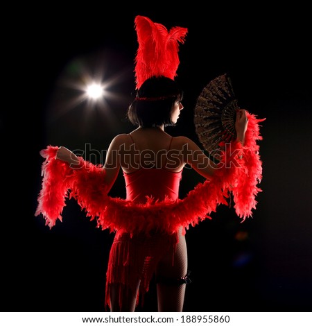 Burlesque dancer with red plumage and red short dress, black and red background, on the stage
