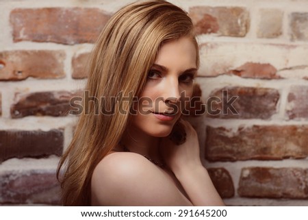 young beautiful girl posing nude against a brick wall studio