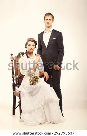 Portrait of young man and woman on vintage chair retro wedding studio
