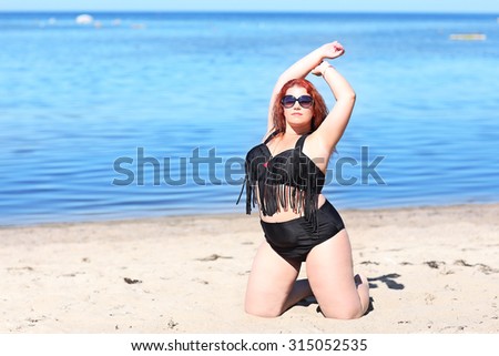 Portrait of red-haired woman in sunglasses resting on beach
