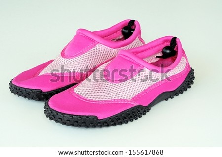 Ladies pink beach shoes against a plain background.