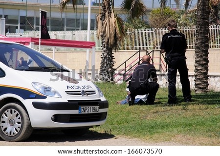 MALAGA, SPAIN - JUNE 14, 2011 - Two police officers talking to a vagrant on the edge of Malagueta beach, Malaga, Spain, June 14, 2011.
