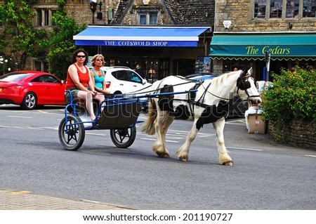 BOURTON ON THE WATER, UK - JUNE 12, 2014 - Tourists taking a ride in a horse and trap around the village, Bourton on the Water, Gloucestershire, England, UK, Western Europe, June 12, 2014.