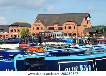 BARTON-UNDER-NEEDWOOD, UK - MAY 21, 2014 - Narrowboats on their moorings with shops, bars and restaurants to the rear, Barton Marina, Barton-under-Needwood, Staffordshire, England, UK, May 21, 2014.