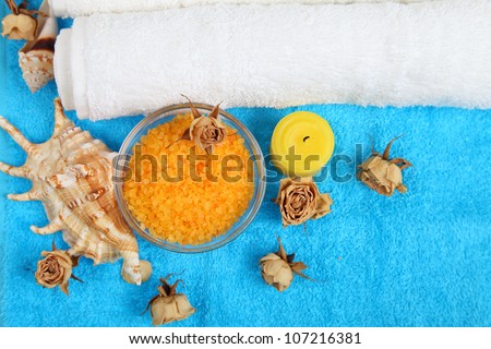 Spa setting with dry roses, sea salt seashell on a blue towel