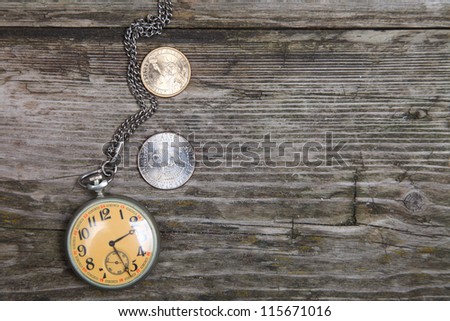 Old clock and U.S. coins on a wooden background