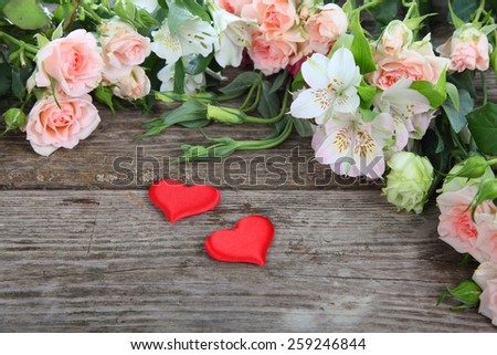 Bouquet of of beautiful flowers and red hearts on a wooden background