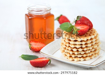Jar of honey, ripe strawberries and waffles. Delicious summer dessert.